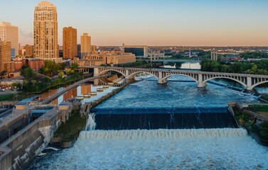 Minneapolis skyline at dawn, St. Anthony Falls dam, powerful water flow. City views, bridges, and...