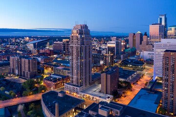 Obraz premium Minneapolis skyline at twilight. City lights illuminate modern and historic buildings. Urban landscape. Downtown West, Minneapolis, Minnesota, United States