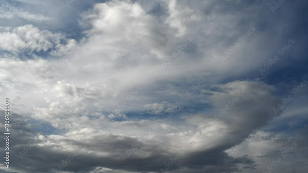 Wall mural time lapse of white and gray clouds moving across a dark blue sky.
