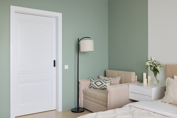 This modern bedroom has a striking green accent wall and a cozy seating area for relaxation