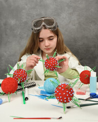 A young science student is learning about viruses and virology structure on a desk with craft and...