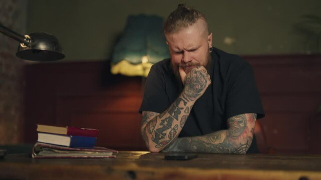 Depressed man looking at screen of mobile phone, waiting for call or message. Portrait of alone frustrated and worried male person sitting at home in night, loneliness and depression, medium shot