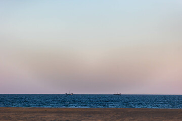 Scenic view of two fishing boats on calm waters during twilight by the shoreline