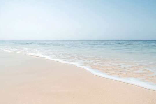 Tranquil beach scene shows soft waves gently washing ashore on light beige sandy beach. Calm ocean water meets clear sky. Peaceful, serene summer vacation ambiance. Ideal for relaxation, rest.
