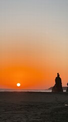 Sunset over a tranquil beach with rock formations on the shoreline