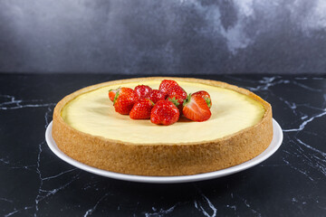 Classic sliced homemade New York cheesecake with fresh strawberries served on a black marble countertop. Homemade dessert.	
