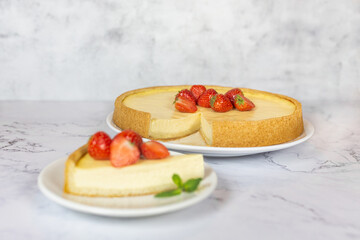 Classic sliced homemade New York cheesecake with fresh strawberries served on a marble countertop. Homemade dessert. 
