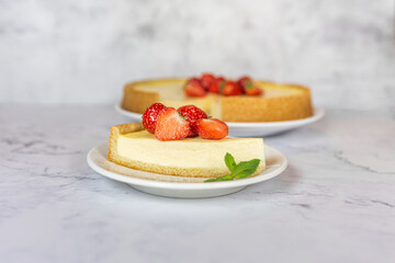 Classic sliced homemade New York cheesecake with fresh strawberries served on a marble countertop. Homemade dessert. 
