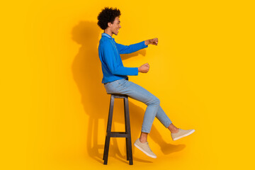 Full length photo of handsome young guy drive car steering wheel chair dressed stylish blue garment isolated on yellow color background