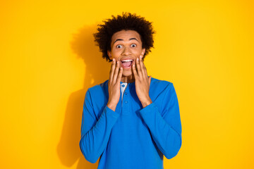 Photo portrait of attractive young man excited touch cheeks dressed stylish blue clothes isolated on yellow color background