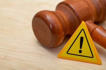 the gavel and the warning sign suggests potential legal consequences or dangers associated with a...