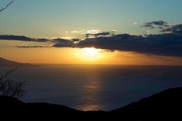 A stunning sunrise over the horizon in Japan, with sunlight reflecting off the ocean and creating a radiant path on the water.