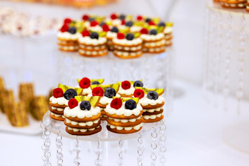 Beautifully arranged dessert table features layered cookies topped with whipped cream fresh berries, creating an inviting atmosphere for guests celebratory event.