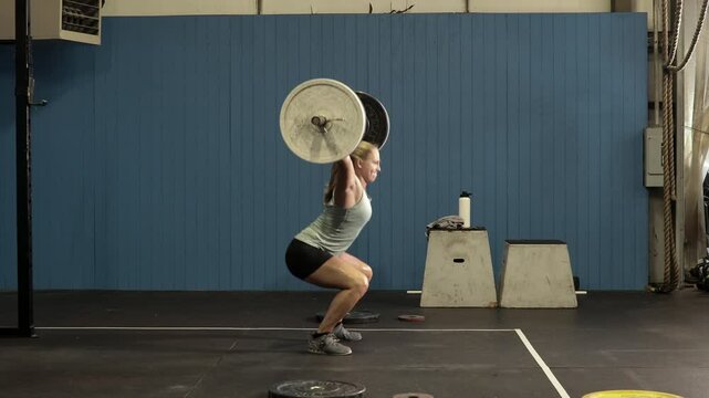 determined female power lifter lifting heavy weights over her head,