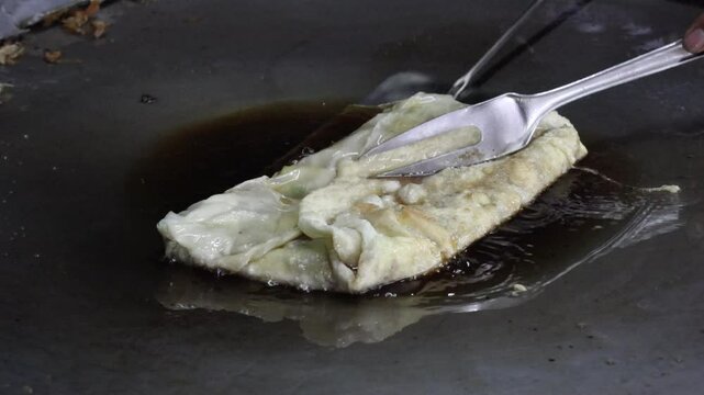 The process of making or cooking an Martabak Telur. Frying with hot oil in a pan, snacks are made from flour filled with eggs, meat, vegetables, and spices.

