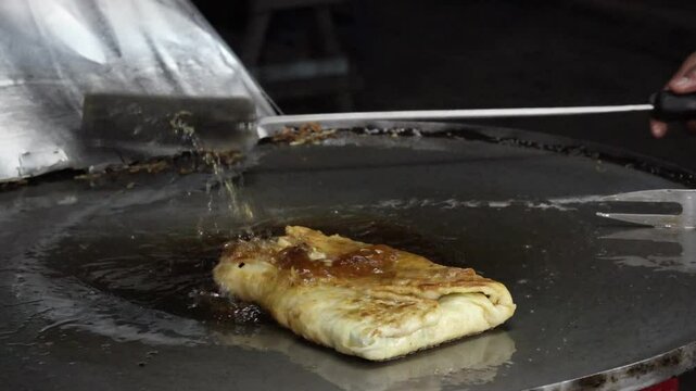 The process of making or cooking an Martabak Telur. Frying with hot oil in a pan, snacks are made from flour filled with eggs, meat, vegetables, and spices.
