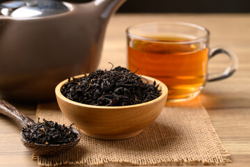 Dried black tea leaves and hot tea drink in cup glass
