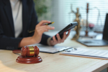 Female lawyer calculating legal fines with a calculator, surrounded by a gavel, pen, documents,...