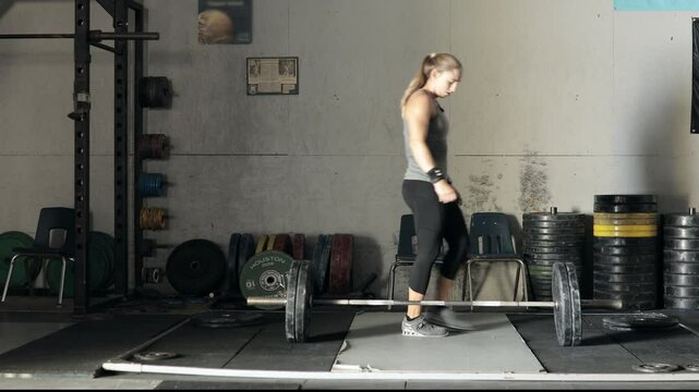 Female weight lifter loading weights onto a bar in the gym
