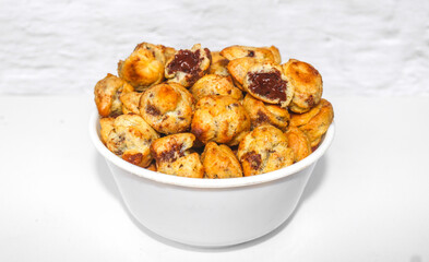Choux Pastry with chocolate filling inside served with a bowl isolated on a white background. Chocolate choux pastry is round in shape