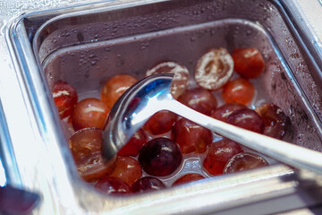 Pieces of grapes in a stainless container are used for topping