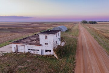 Abandoned buildings on a rural road, empty fields, late afternoon light. Sage Creek, Interior, South Dakota, USA.
