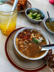Soto Kudus, a traditional Indonesian chicken soup, served with side dishes. Indonesian cuisine.