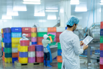 A factory worker wearing protective gear, organizing colorful storage crates in a clean and modern industrial facility, showcasing efficiency, cleanliness, and organization in industrial operations.