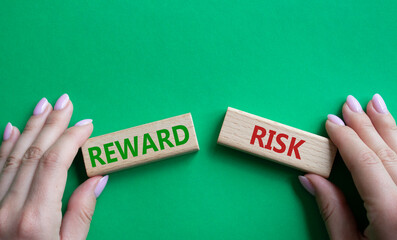 Risk or Reward symbol. Concept word Risk or Reward on wooden blocks. Businessman hand. Beautiful green background. Business and Risk or Reward concept. Copy space