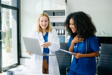  Doctors and nurses using laptops and clipboards, showcasing teamwork, modern healthcare.