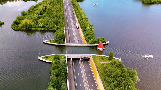 Experience the stunning Veluwemeer Aqueduct in the Netherlands, where a road elegantly crosses under water. Boats pass below, showcasing the clever integration of nature and infrastructure.