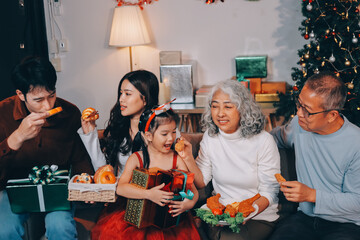 Portrait of Asian family exchanging presents during christmas at home. Attractive happy people holding gift box, celebrate holiday thanksgiving, xmas eve tradition in living room in house together.