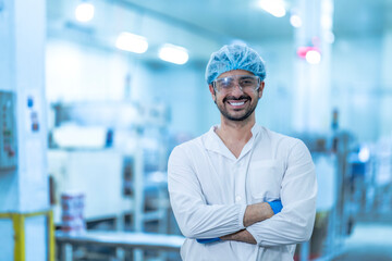 A confident food processing supervisor in protective gear, standing with arms crossed next to machinery in a factory, symbolizing leadership, quality assurance, and operational safety.