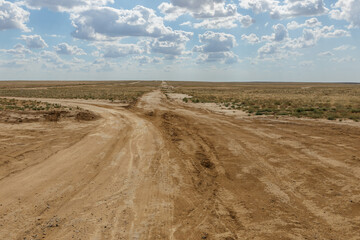 Rugged dirt roads intersecting in the vast steppe landscape of Kazakhstan under a cloudy sky
