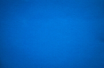 Photo of the texture of the blue background of a soft felt fabric. Pure blue cardboard.