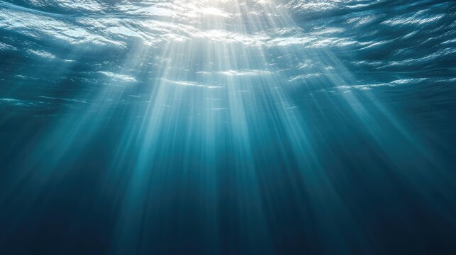 Blue underwater surface illuminated by sunlight beams creating an ethereal abstract backdrop for creative projects or serene designs