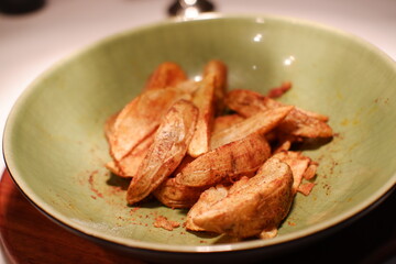 Fried potatoes in a green plate on a wooden table