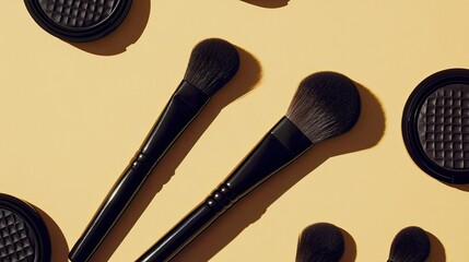 Still life featuring sleek black makeup brushes and textured matte compacts, geometric placement on tan background