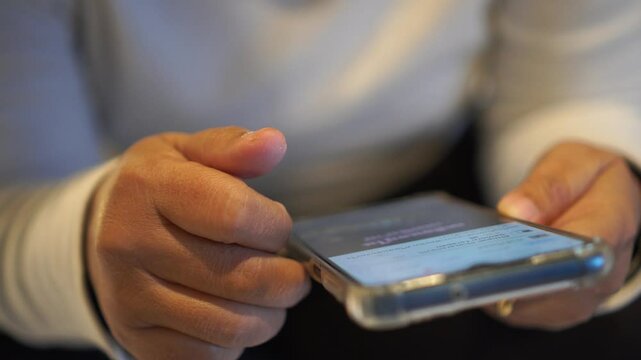 Hands holding smartphone pressing fingerers, reading social media internet, typing shopping online at home