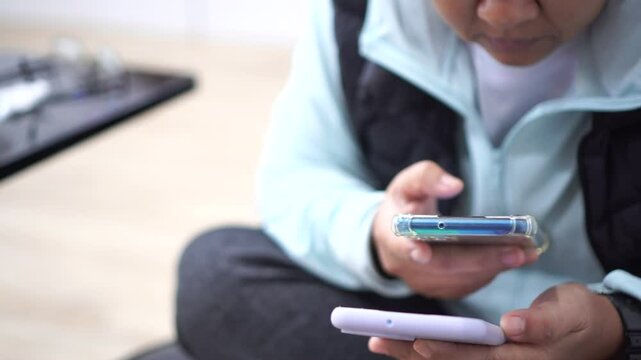 Senior Asian Using two smartphone for scan application technology and money transfer. Touching gadget choose app on mobile phone