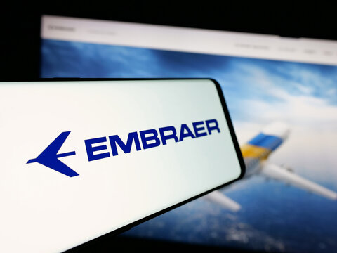 Stuttgart, Germany - 12-16-2024: Mobile phone with logo of Brazilian aerospace company Embraer SA on screen in front of business website. Focus on center-left of phone display.