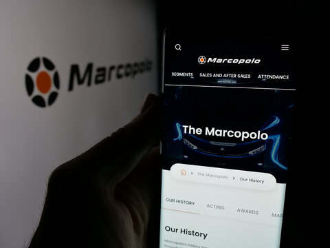 Stuttgart, Germany - 12-19-2024: Person holding mobile phone with website of Brazilian automotive company Marcopolo SA on screen with logo. Focus on center of phone display.