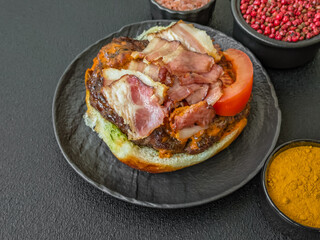 Juicy burger with beef patty, tomatoes, cheese, bacon, salt and spices