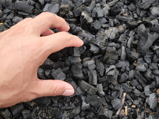 wood charcoal with a beautiful natural background. Pile of natural wood charcoal isolated on black sand background. Hardwood charcoal.