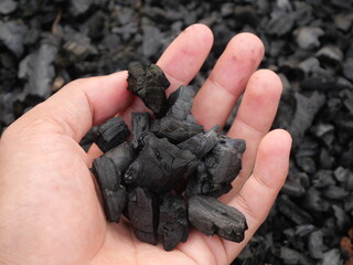 wood charcoal with a beautiful natural background. Pile of natural wood charcoal isolated on black sand background. Hardwood charcoal.