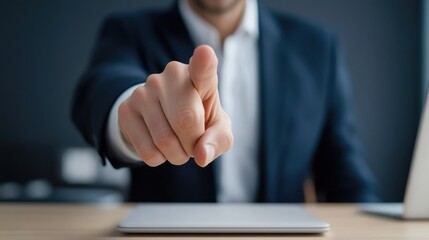 Obraz premium Business professional in dark suit pointing finger at viewer with laptop on desk in modern office environment