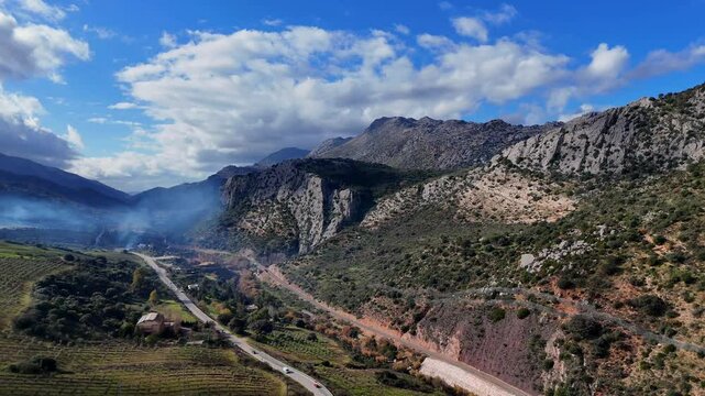 Drohnenflug &uuml;ber die Ebene von Ronda: Olivenplantagen, Bergpanorama, Rauchender Horizont und malerische Stra&szlig;en in Spaniens mediterraner Landschaft