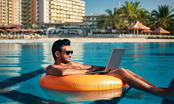 A guy is relaxing with a computer in the sea water against the backdrop of a beach and a hotel. A man with a laptop on an inflatable ring in the sea.