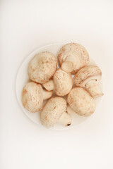 Fresh champignons on a white plate. Mushrooms on a white background.