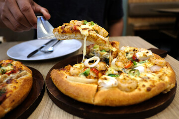 A vegetarian pizza and a seafood pizza are on a wooden table in a pizzeria